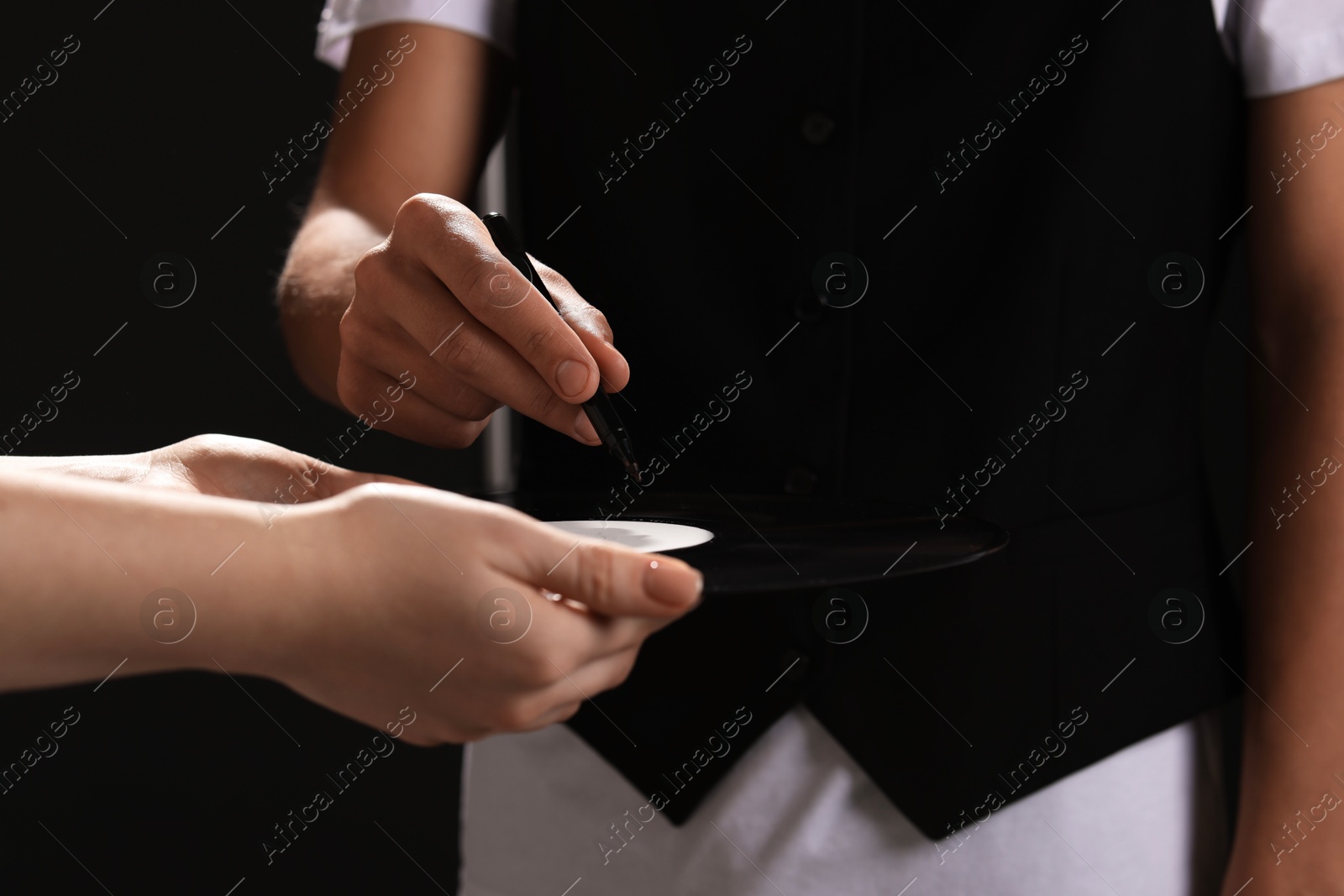 Photo of Singer signing autograph on vinyl record against black background, closeup