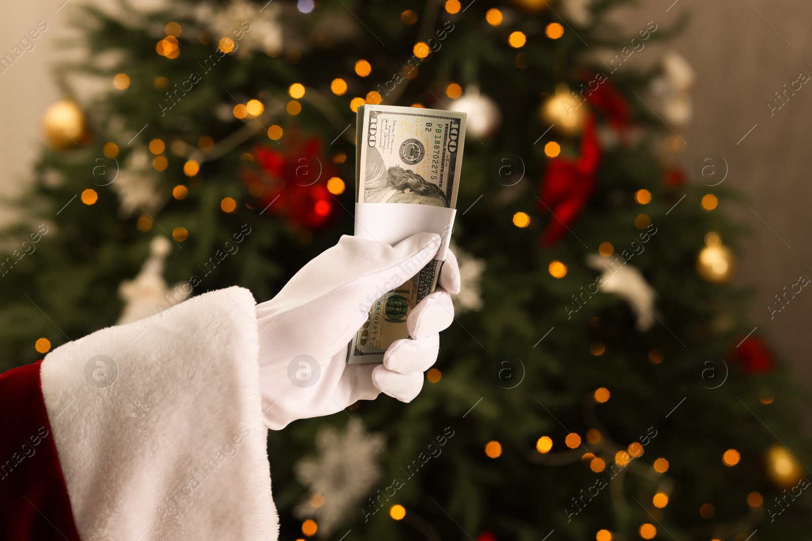 Photo of Santa Claus with dollar banknotes near Christmas tree indoors, closeup. Space for text