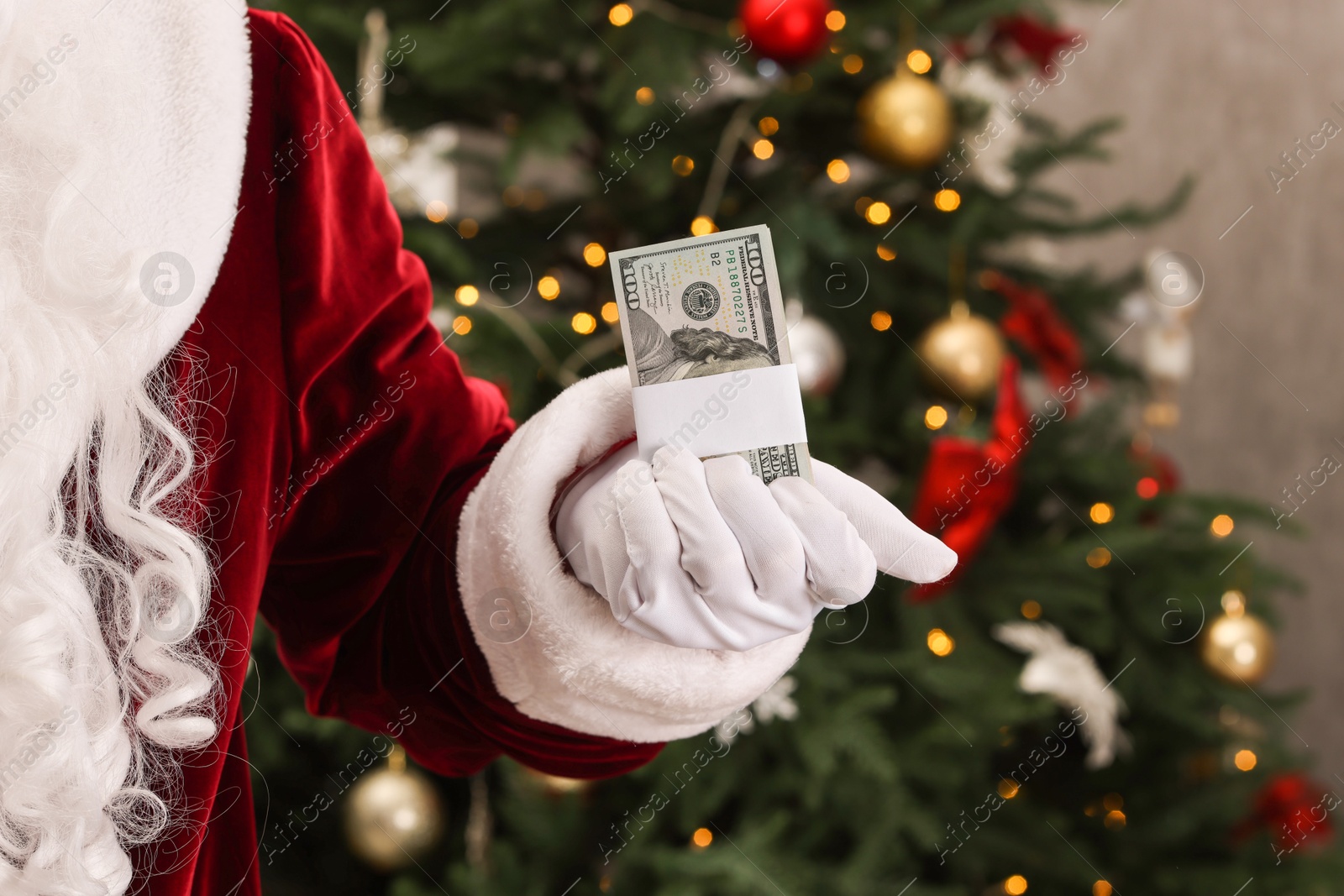 Photo of Santa Claus with dollar banknotes near Christmas tree indoors, closeup