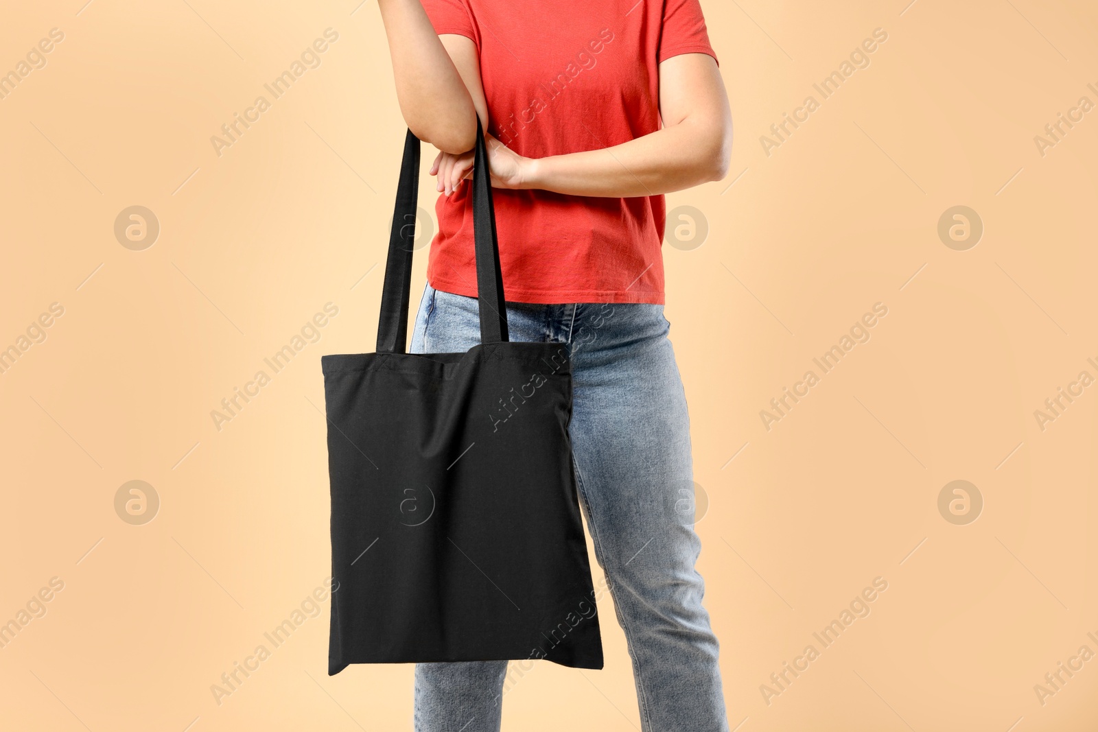 Photo of Woman with blank black shopper bag on color background, closeup. Mockup for design