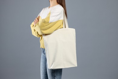 Photo of Woman with blank shopper bag on grey background, closeup. Mockup for design