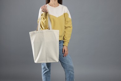 Photo of Woman with blank shopper bag on grey background, closeup. Mockup for design