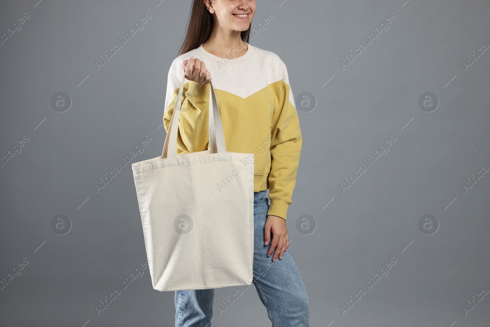 Photo of Woman with blank shopper bag on grey background, closeup. Mockup for design