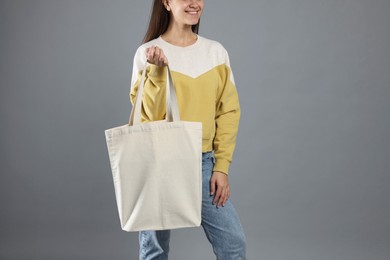 Photo of Woman with blank shopper bag on grey background, closeup. Mockup for design