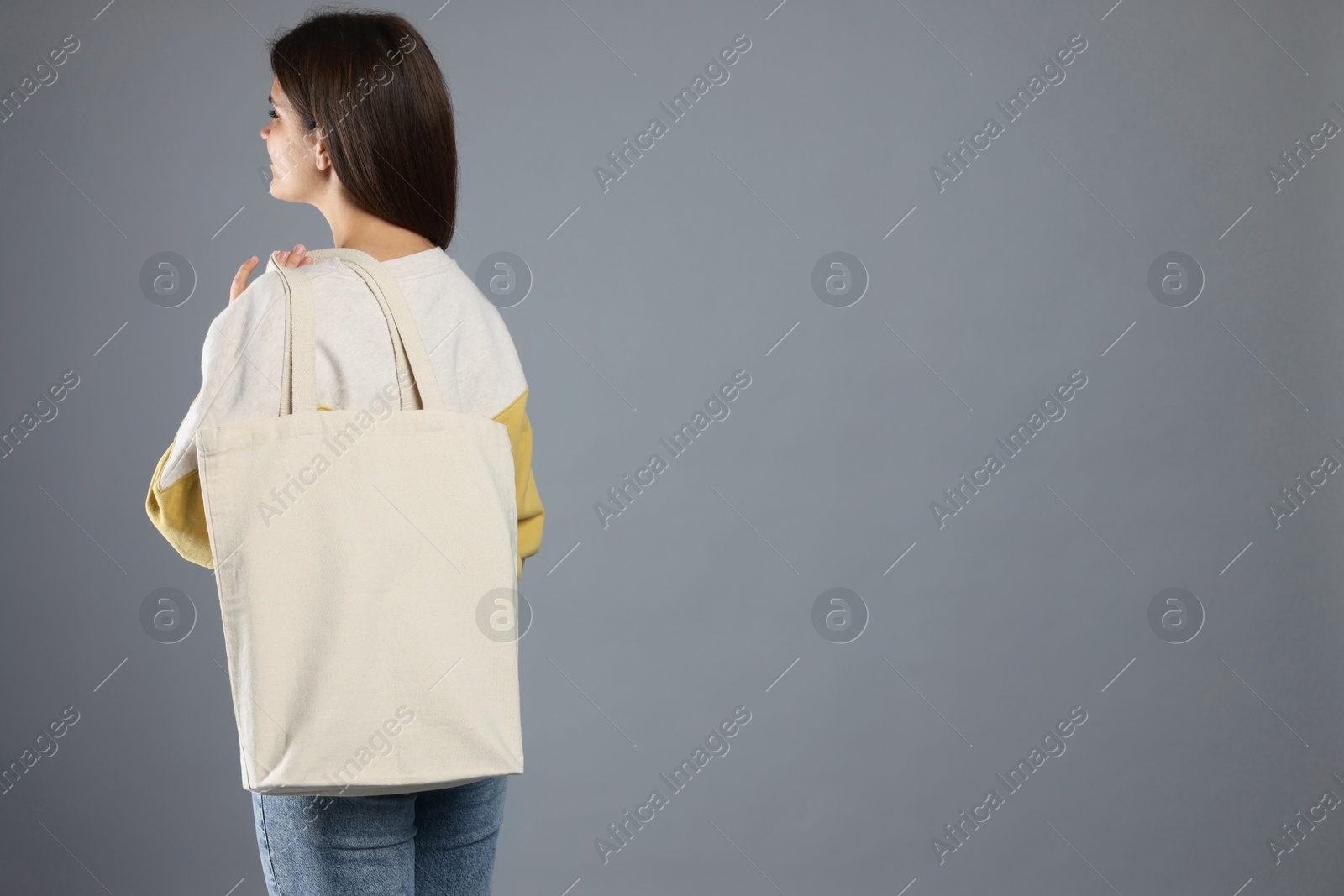 Photo of Woman with blank shopper bag on grey background, back view. Mockup for design