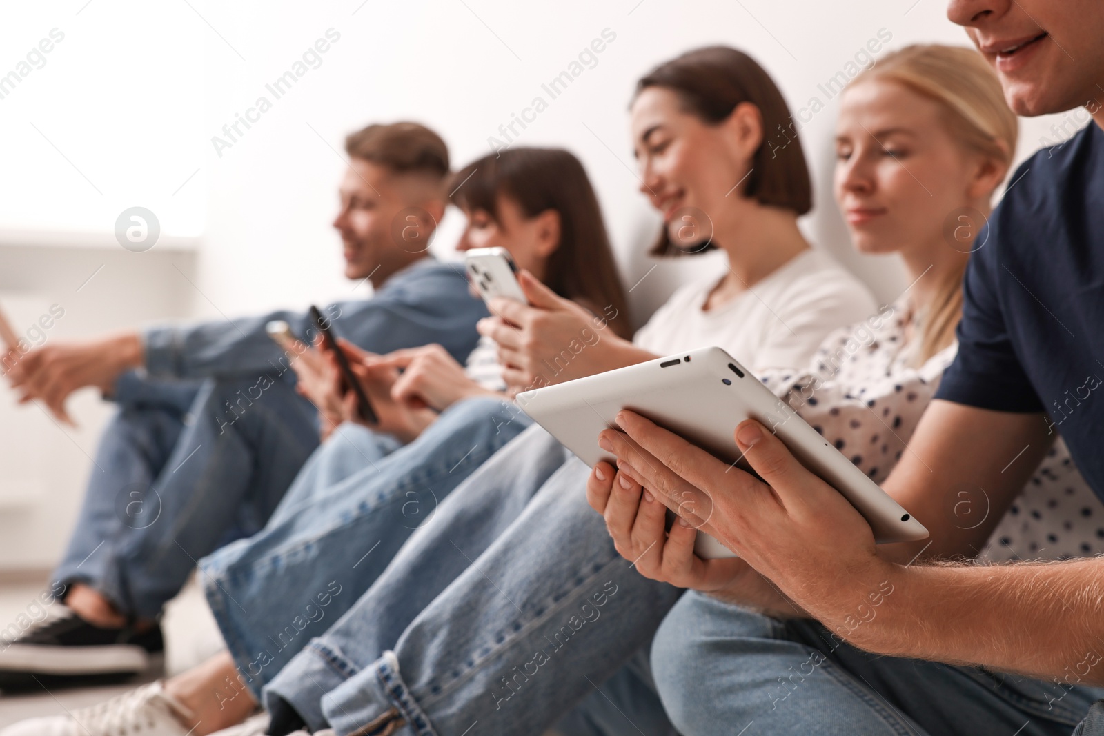 Photo of Group of people using different gadgets on floor indoors. Modern technology