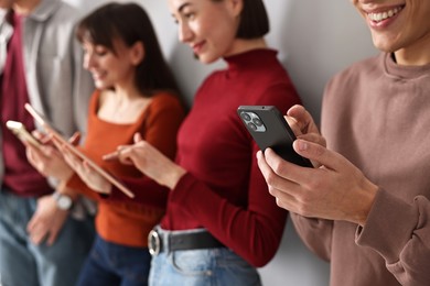 Group of people using different gadgets near light wall indoors. Modern technology