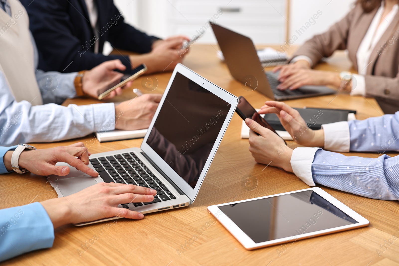 Photo of Group of people using different gadgets at wooden table in office, closeup. Modern technology