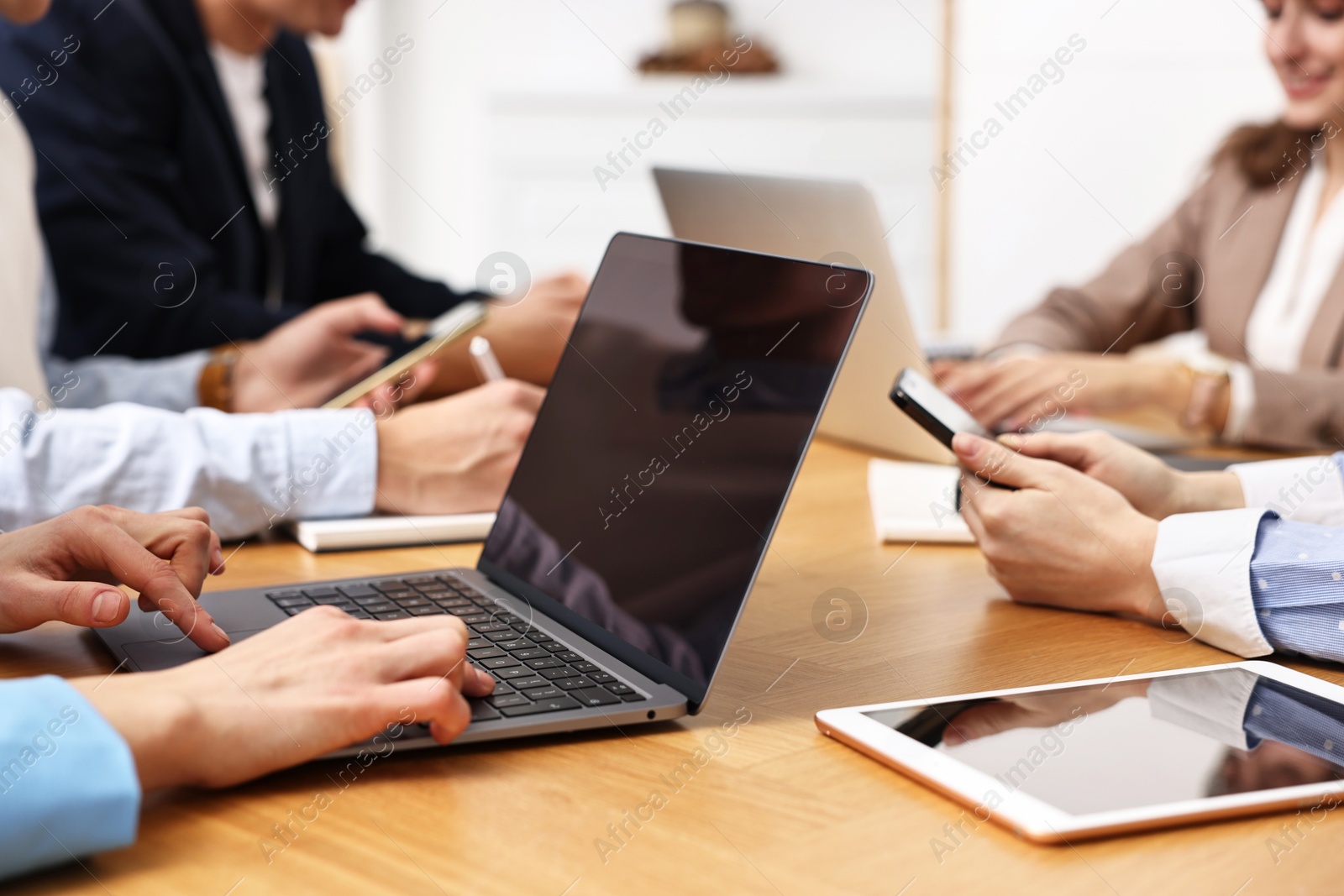 Photo of Group of people using different gadgets at wooden table in office, closeup. Modern technology