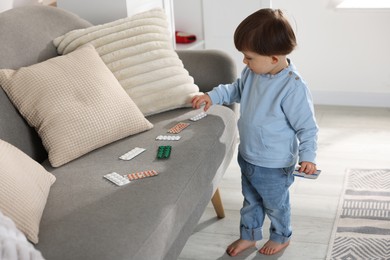 Photo of Little boy playing with pills at home. Child in danger