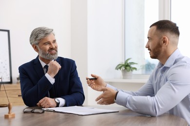 Photo of Man having meeting with professional lawyer at wooden desk indoors