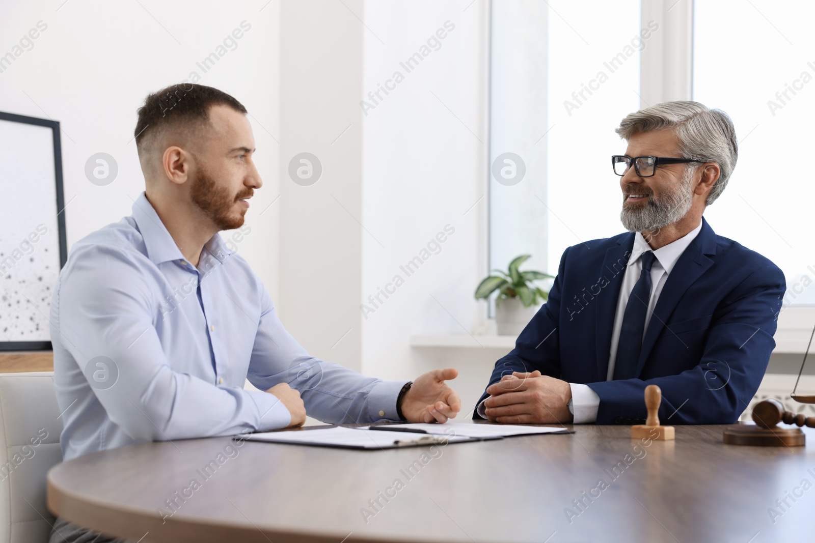 Photo of Man having meeting with professional lawyer at wooden desk indoors