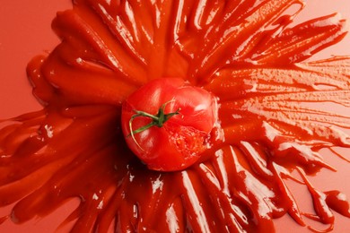 Photo of Tasty ketchup and tomato on red background, top view