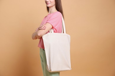 Woman with blank shopper bag on beige background, closeup. Mockup for design