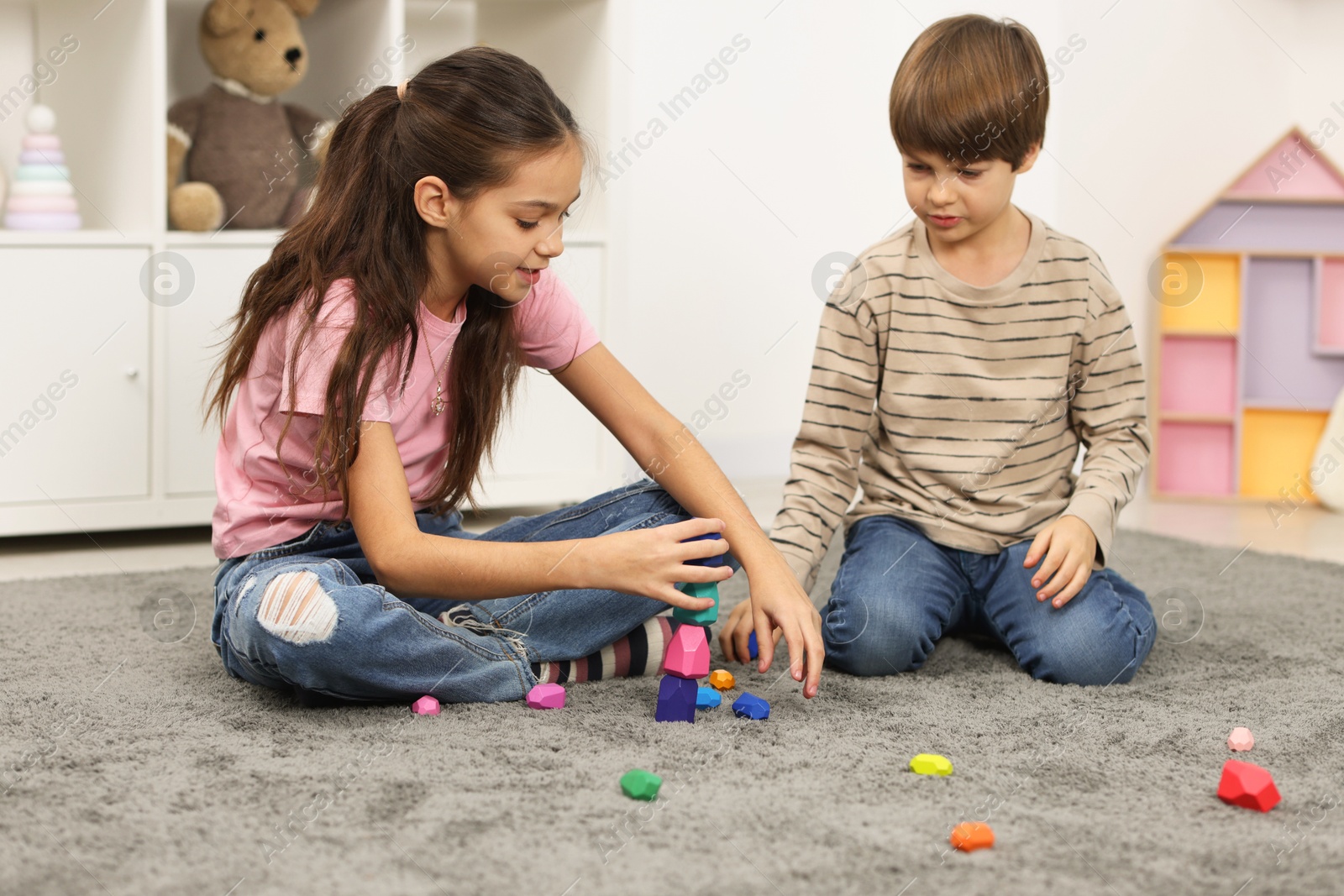 Photo of Children playing with balancing stones on floor indoors