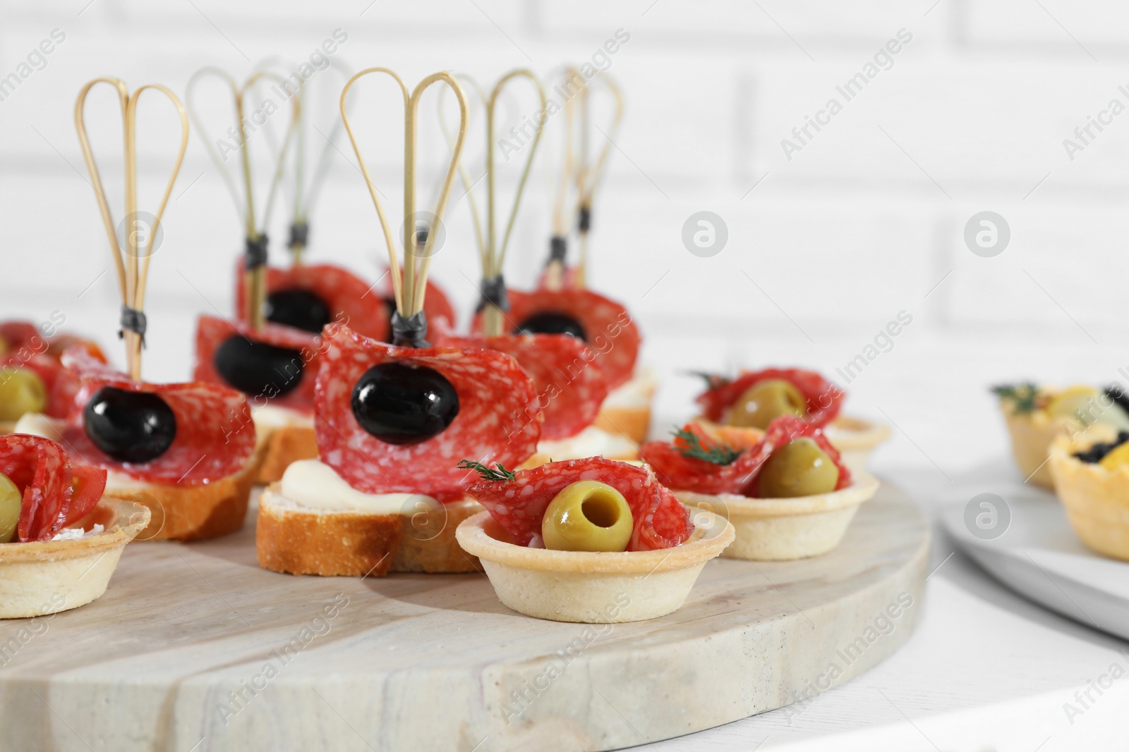 Photo of Many different tasty canapes on white wooden table, closeup