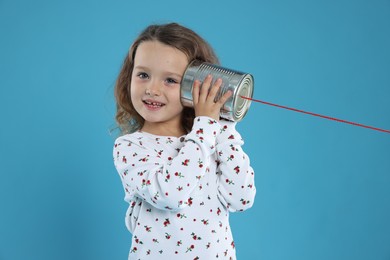 Photo of Girl using tin can telephone on blue background