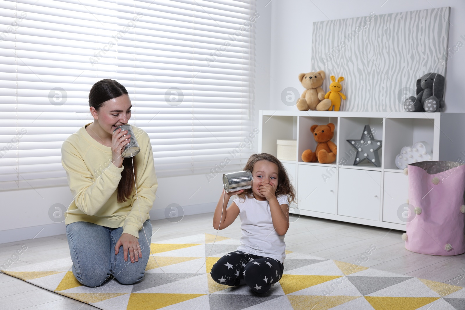 Photo of Woman and girl talking on tin can telephone indoors