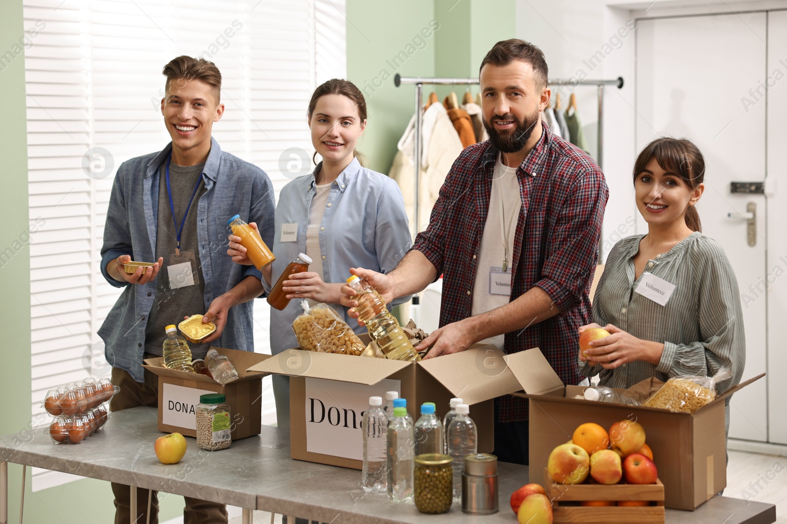 Photo of Group of volunteers packing food donations at table indoors