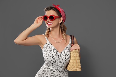 Photo of Happy pin-up woman with bag posing on grey background