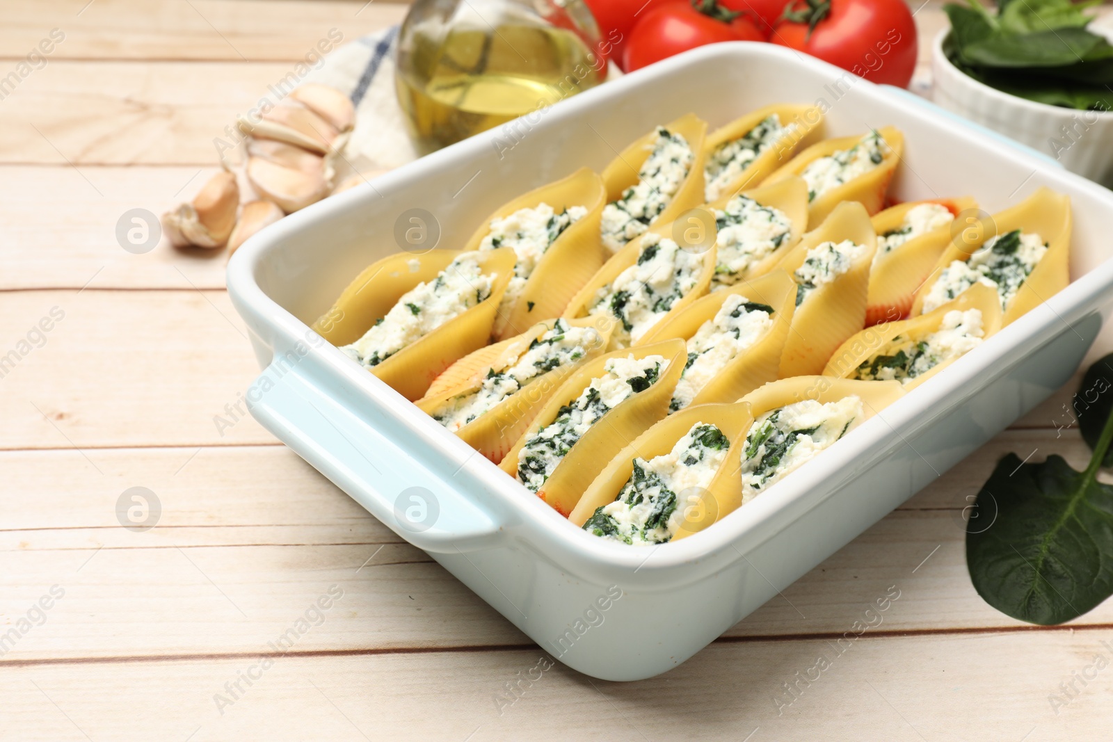 Photo of Delicious pasta with ricotta cheese and spinach in baking dish on wooden table, closeup