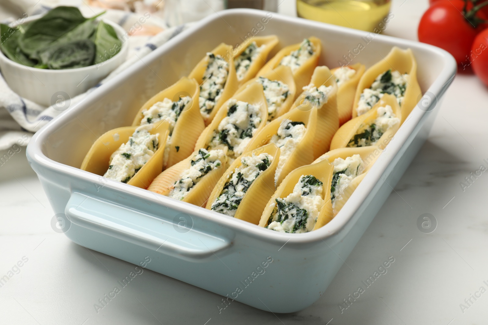 Photo of Delicious conchiglie pasta with ricotta cheese and spinach in baking dish on white marble table, closeup