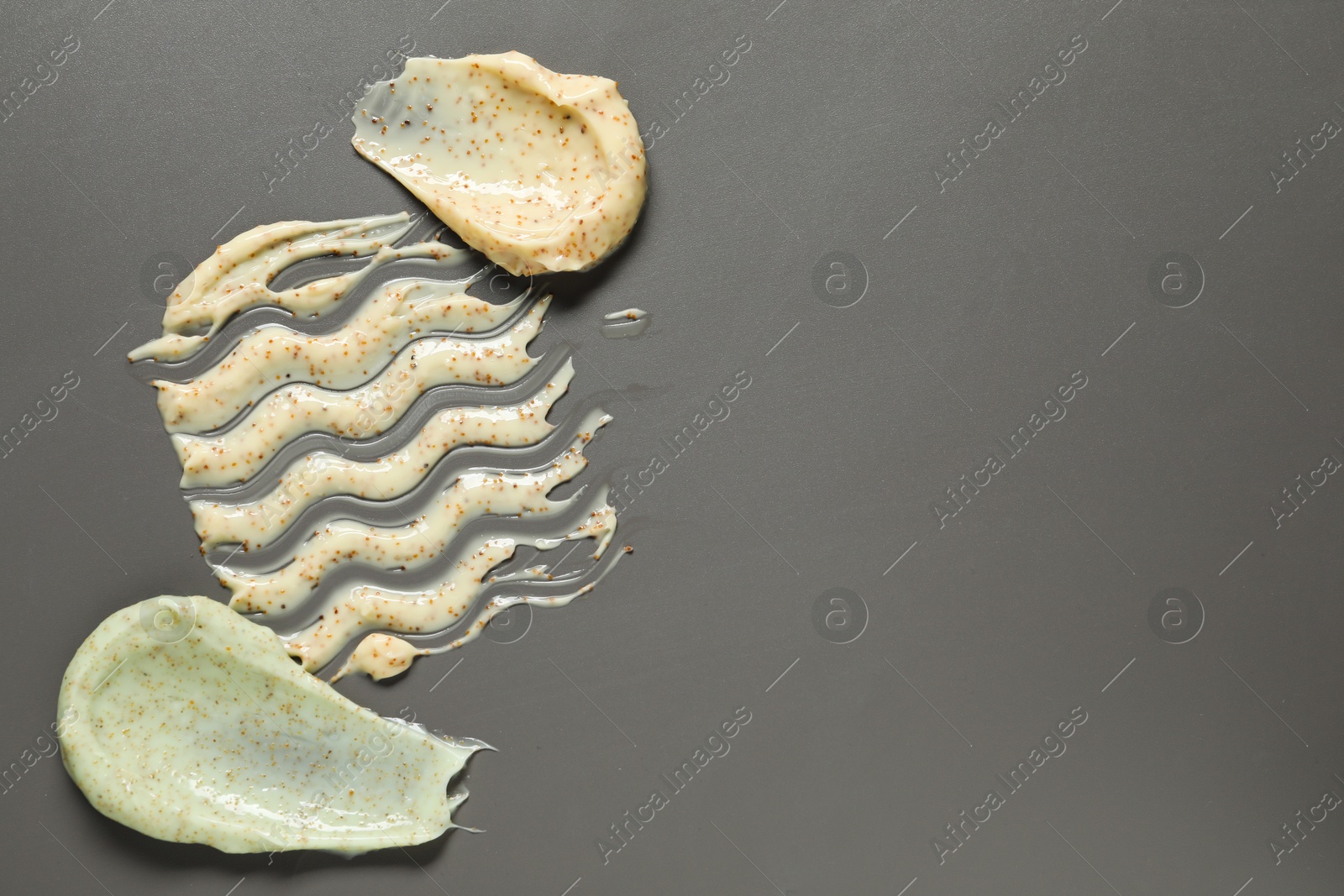 Photo of Samples of body scrubs on grey background, top view. Space for text