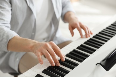 Photo of Man playing synthesizer indoors, closeup. Electronic musical instrument