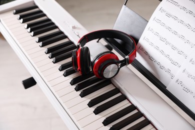 Photo of Synthesizer with music sheets and headphones indoors, closeup