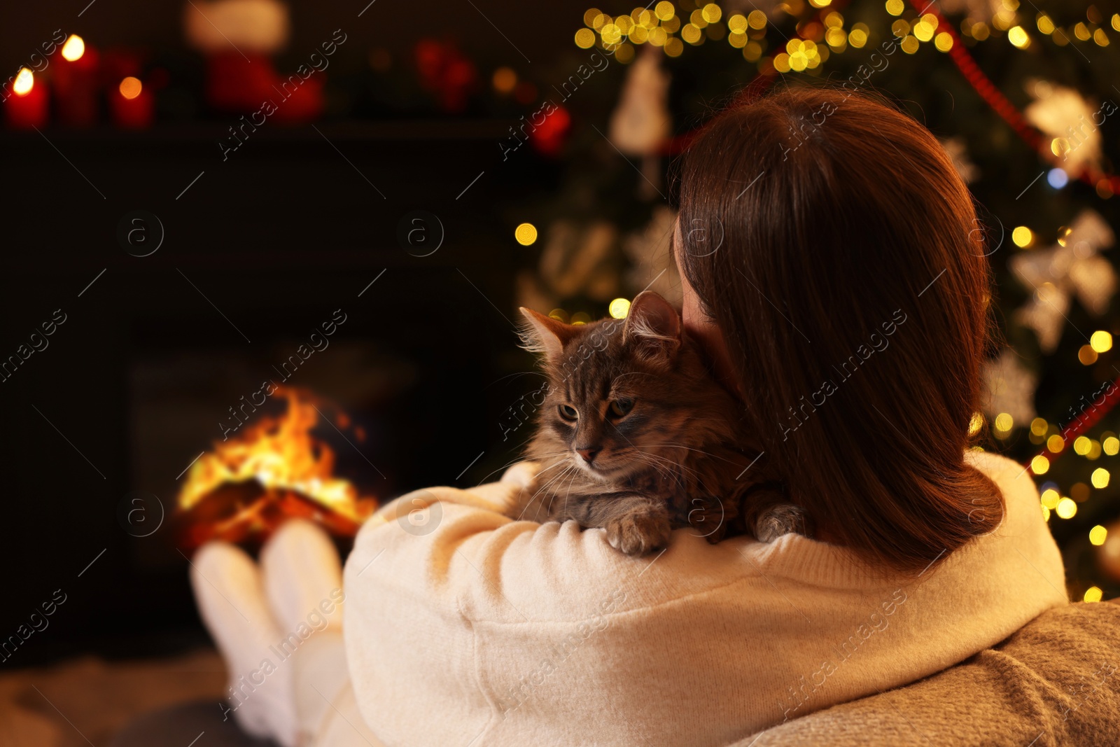 Photo of Woman with cute cat in room decorated for Christmas, space for text