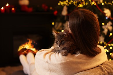 Photo of Woman with cute cat in room decorated for Christmas, space for text