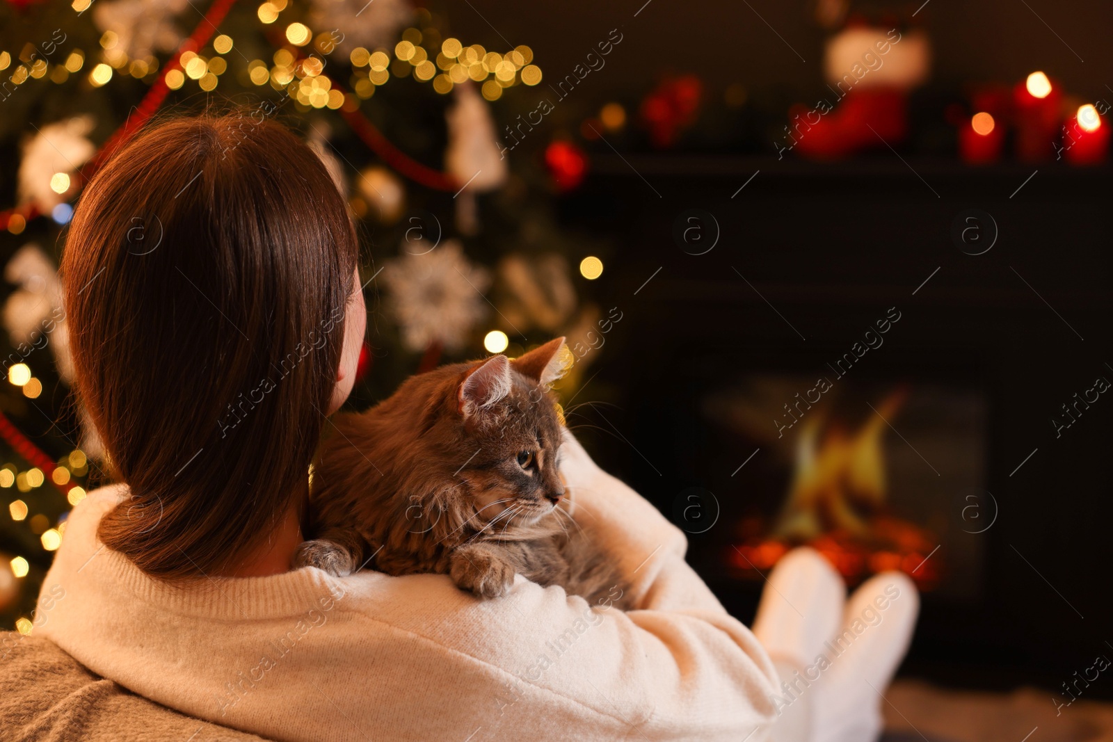 Photo of Woman with cute cat in room decorated for Christmas, space for text