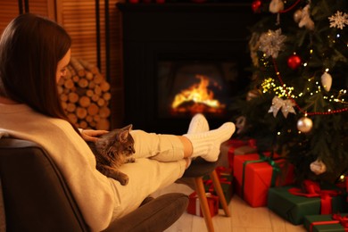 Photo of Woman with cute cat in room decorated for Christmas, space for text