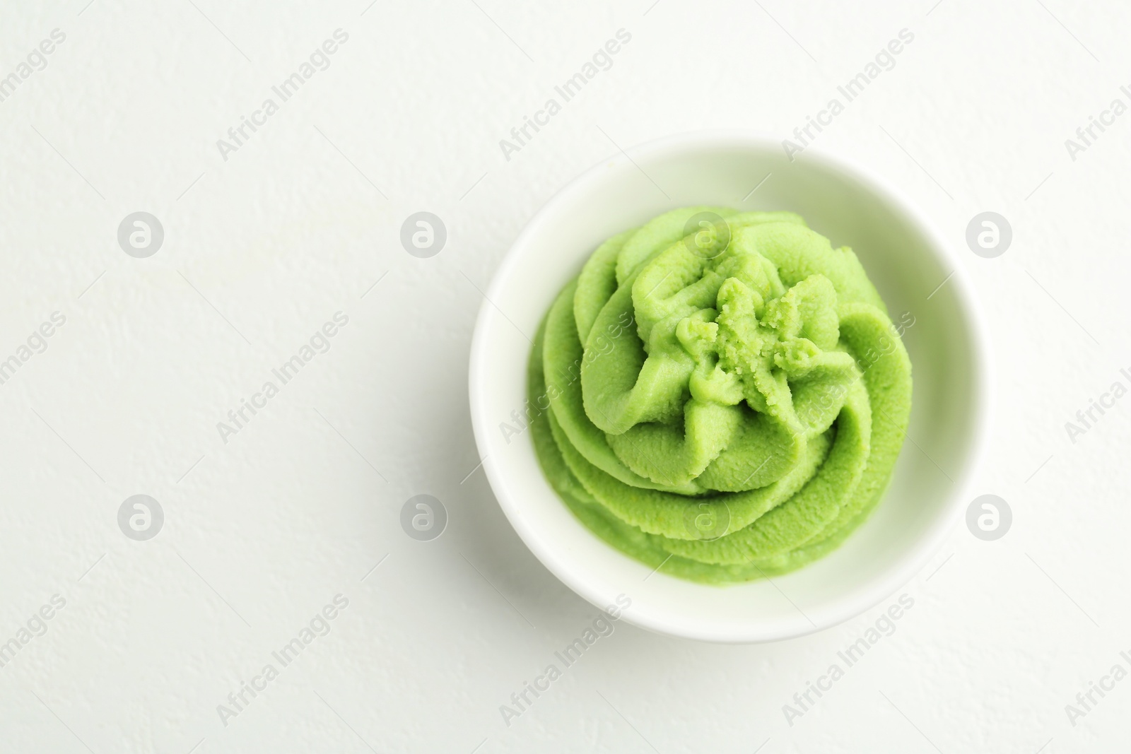 Photo of Hot wasabi paste in bowl on light textured table, top view. Space for text