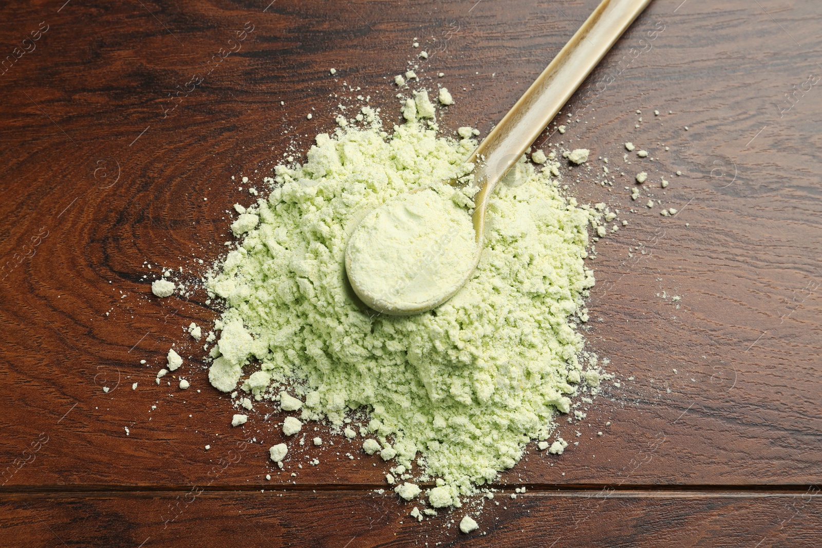 Photo of Pile of dry wasabi powder and spoon on wooden table, top view