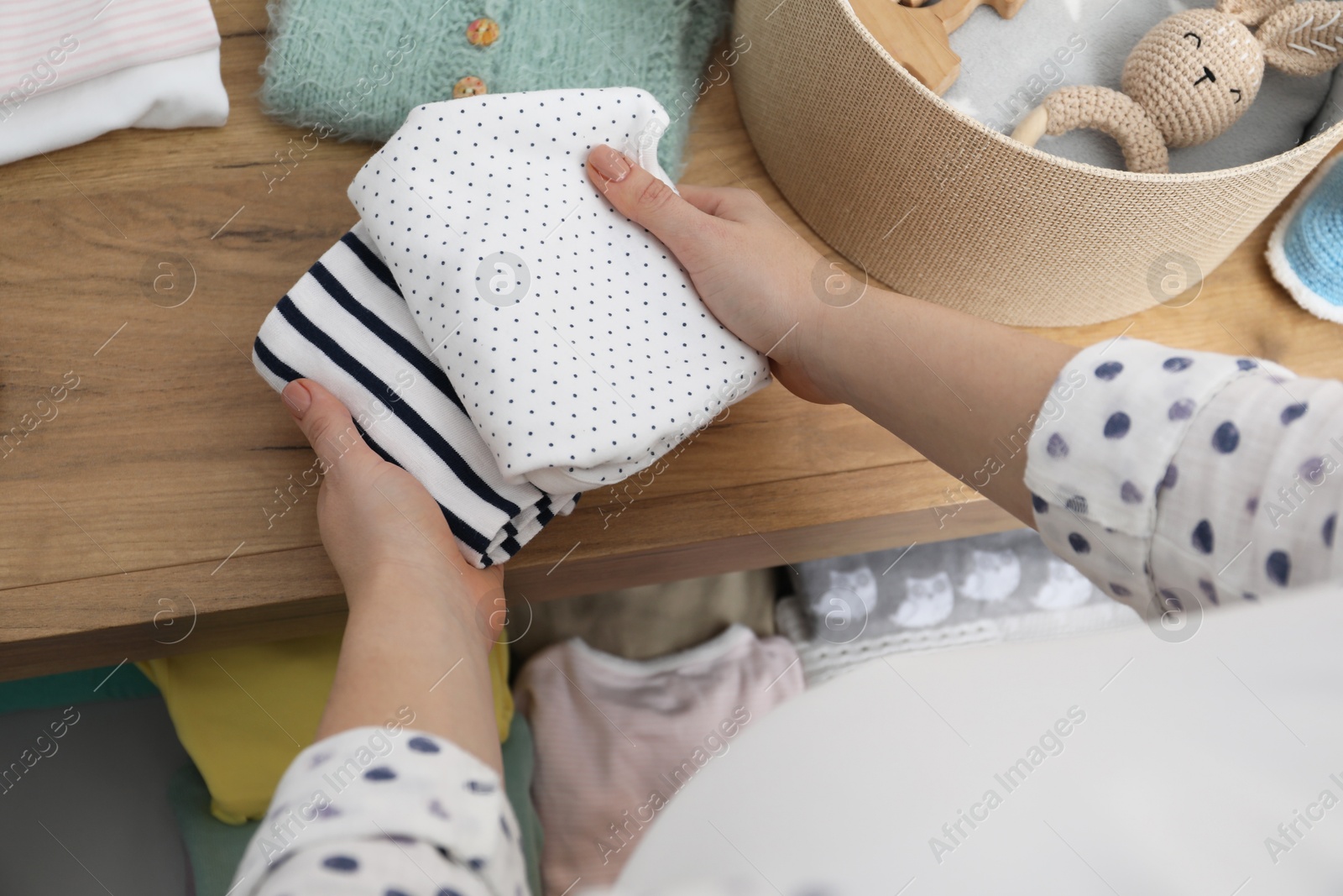 Photo of Pregnant woman with baby clothes at home, closeup