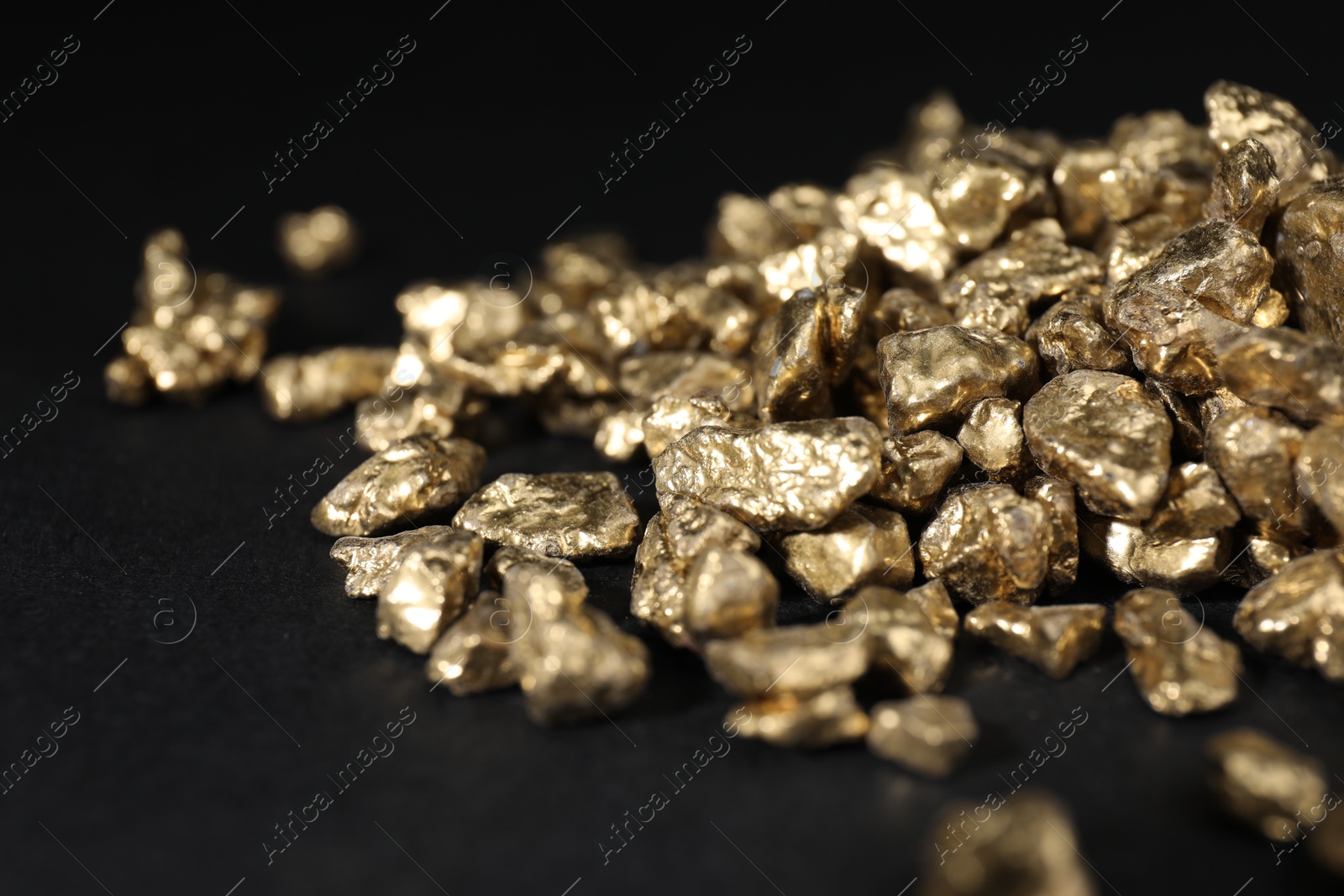 Photo of Shiny gold nuggets on black table, closeup