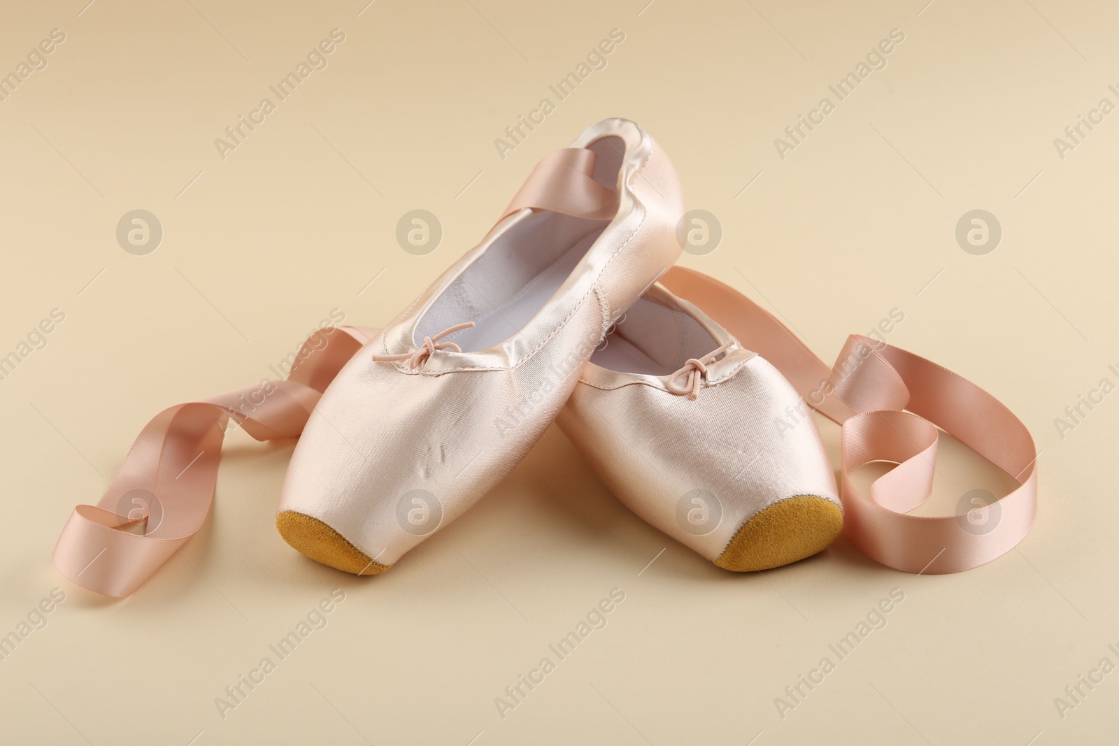 Photo of Pair of beautiful pointe shoes on beige background