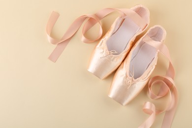 Photo of Pair of beautiful pointe shoes on beige background, top view. Space for text