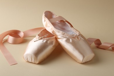 Photo of Pair of beautiful pointe shoes on beige background, closeup