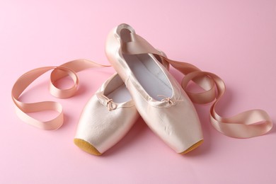 Photo of Pair of beautiful pointe shoes on pink background