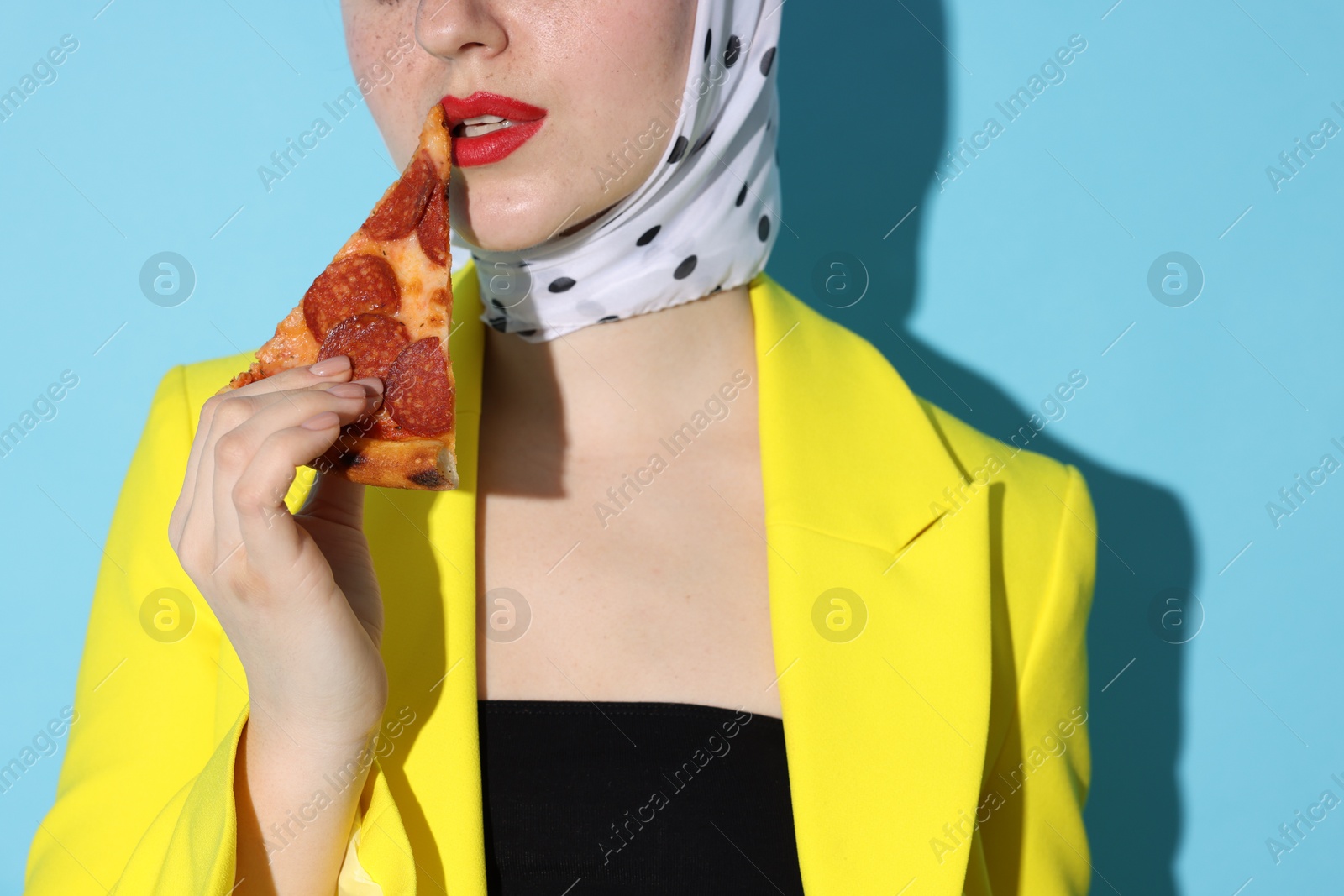 Photo of Stylish woman with piece of pizza on light blue background, closeup