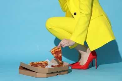 Photo of Stylish woman with delicious pizza on light blue background, closeup