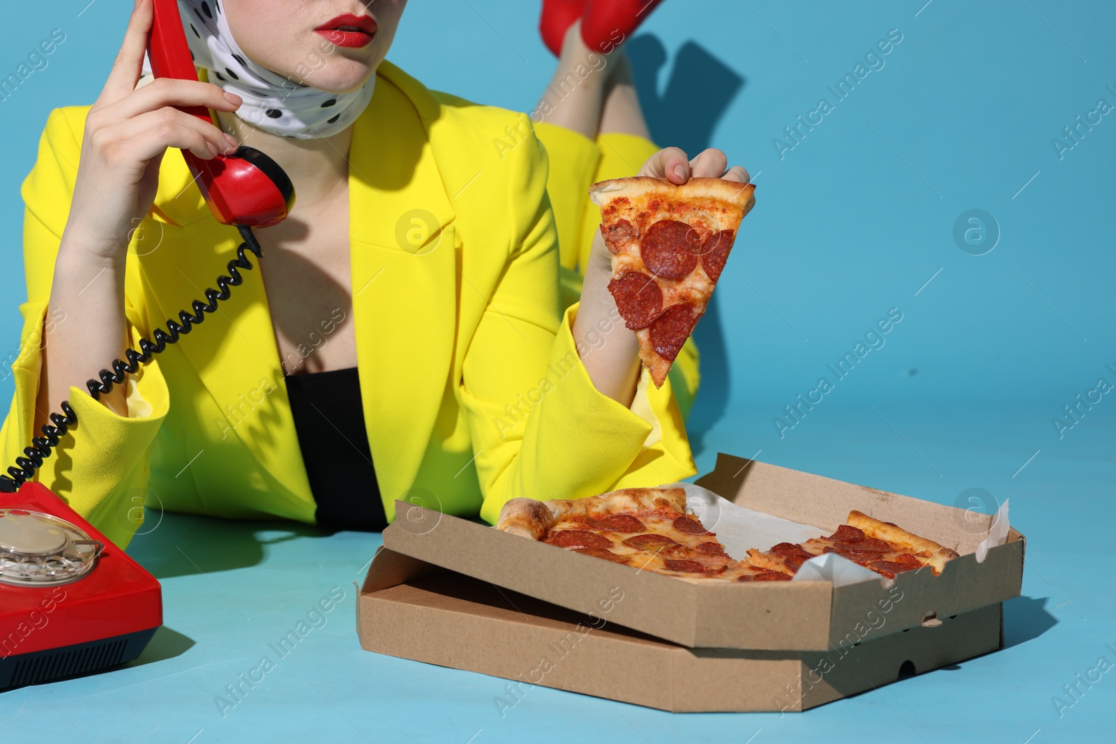 Photo of Woman with delicious pizza and telephone on light blue background, closeup