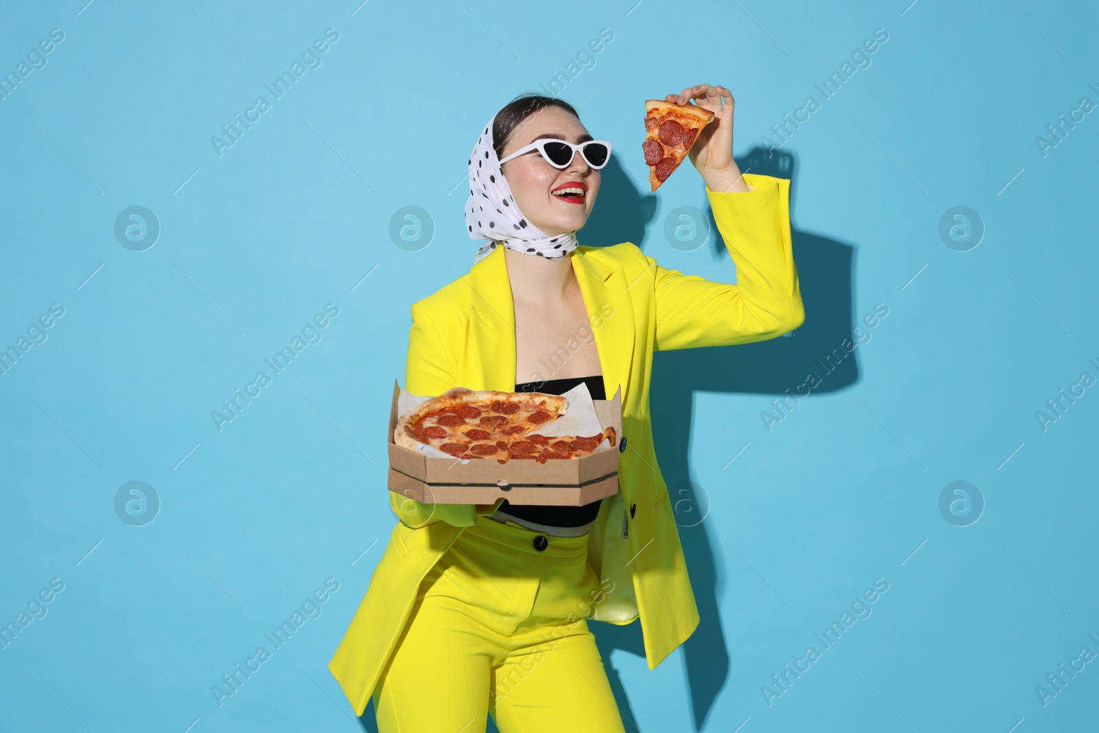 Photo of Stylish woman with delicious pizza on light blue background