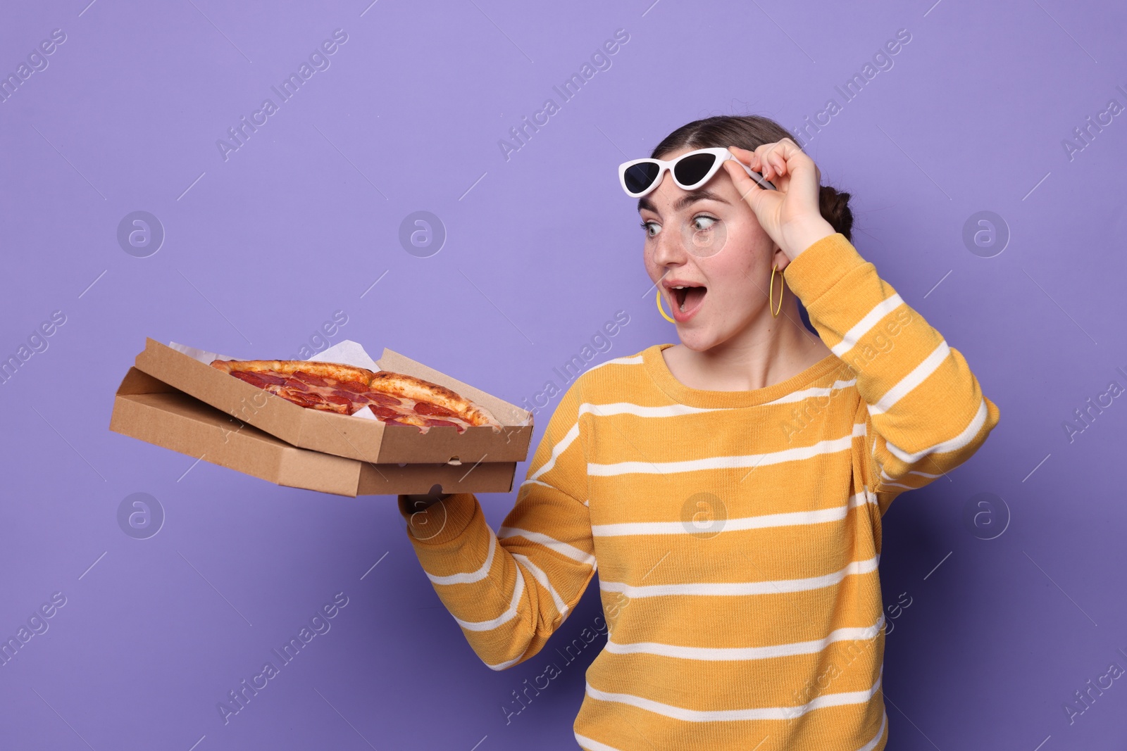 Photo of Surprised woman with delicious pizza on violet background