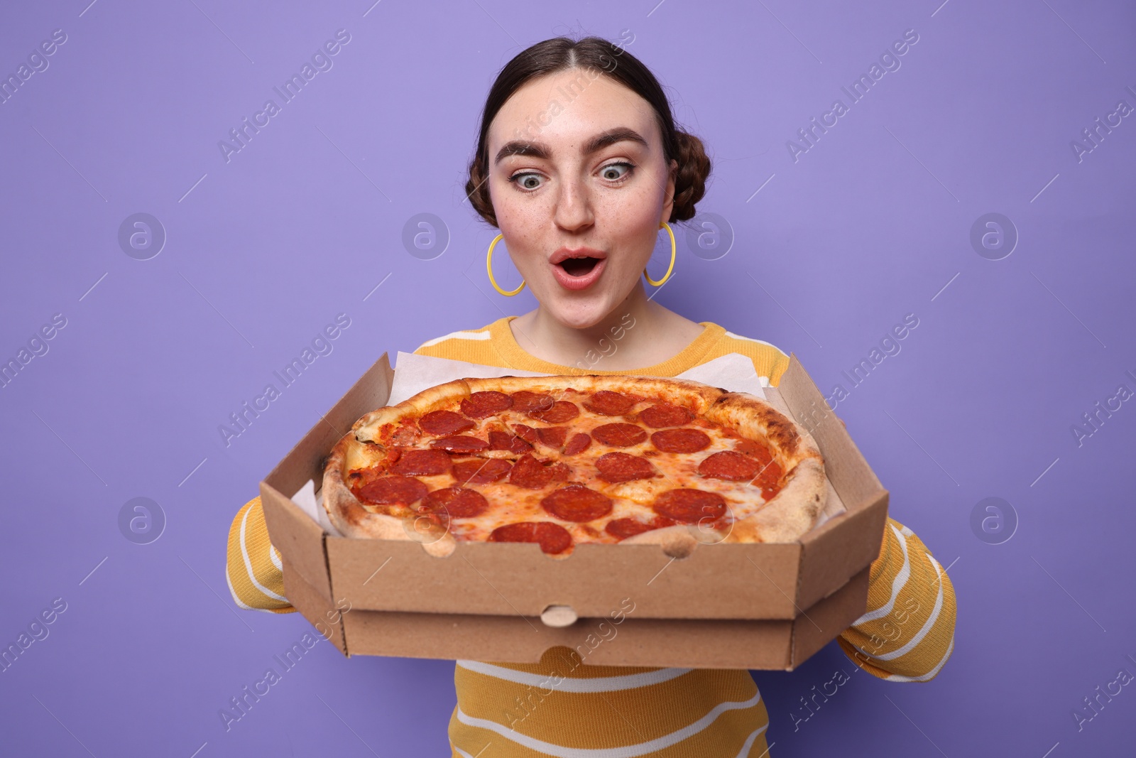 Photo of Surprised woman with delicious pizza on violet background