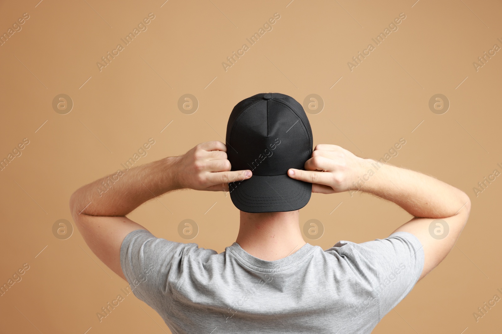 Photo of Man in stylish baseball cap on beige background, back view. Mockup for design