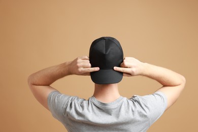 Man in stylish baseball cap on beige background, back view. Mockup for design