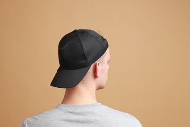 Photo of Man in stylish baseball cap on beige background, back view. Mockup for design